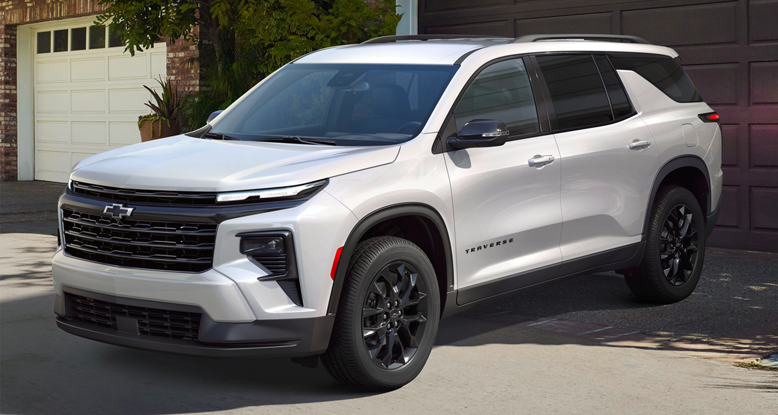 A silver Chevy Traverse parked in front of a house's garage