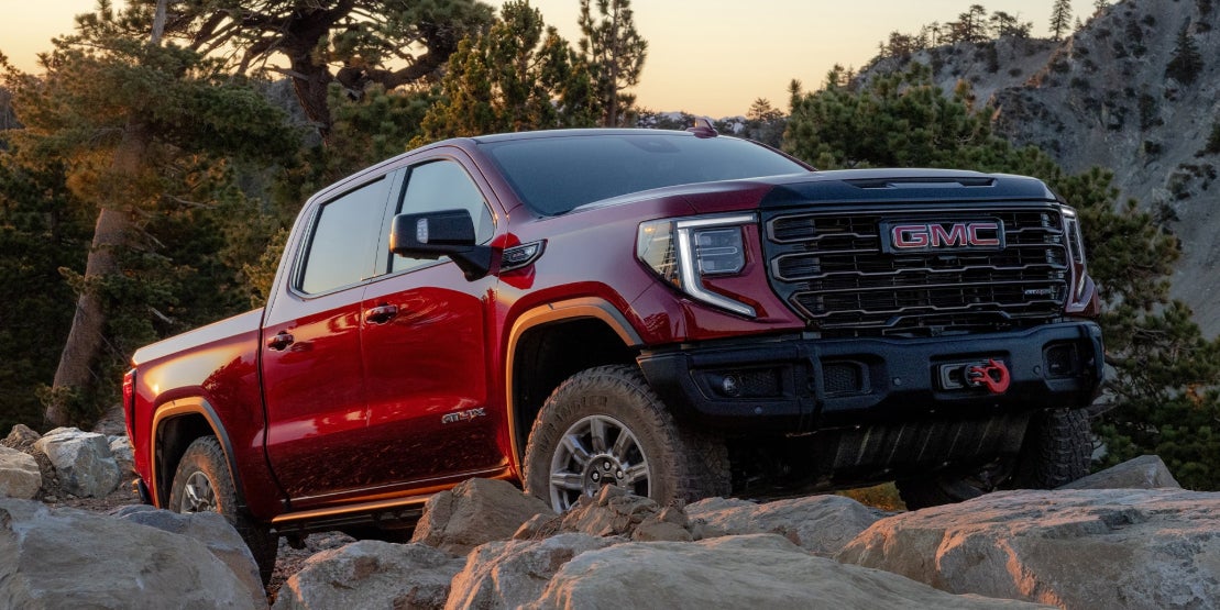 A red GMC Sierra 1500 parked on a rocky outcrop.